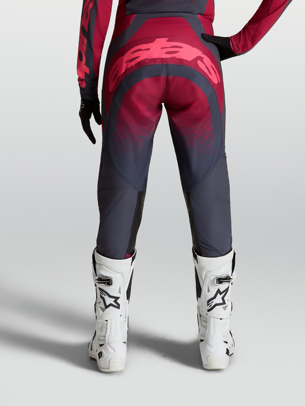 Alpinestars Pantaloni Stella Techstar Swan, pantaloni motocross da donna, grigio e cremisi, vista posteriore su modella con stivali bianchi, abbigliamento off-road ad alte prestazioni.