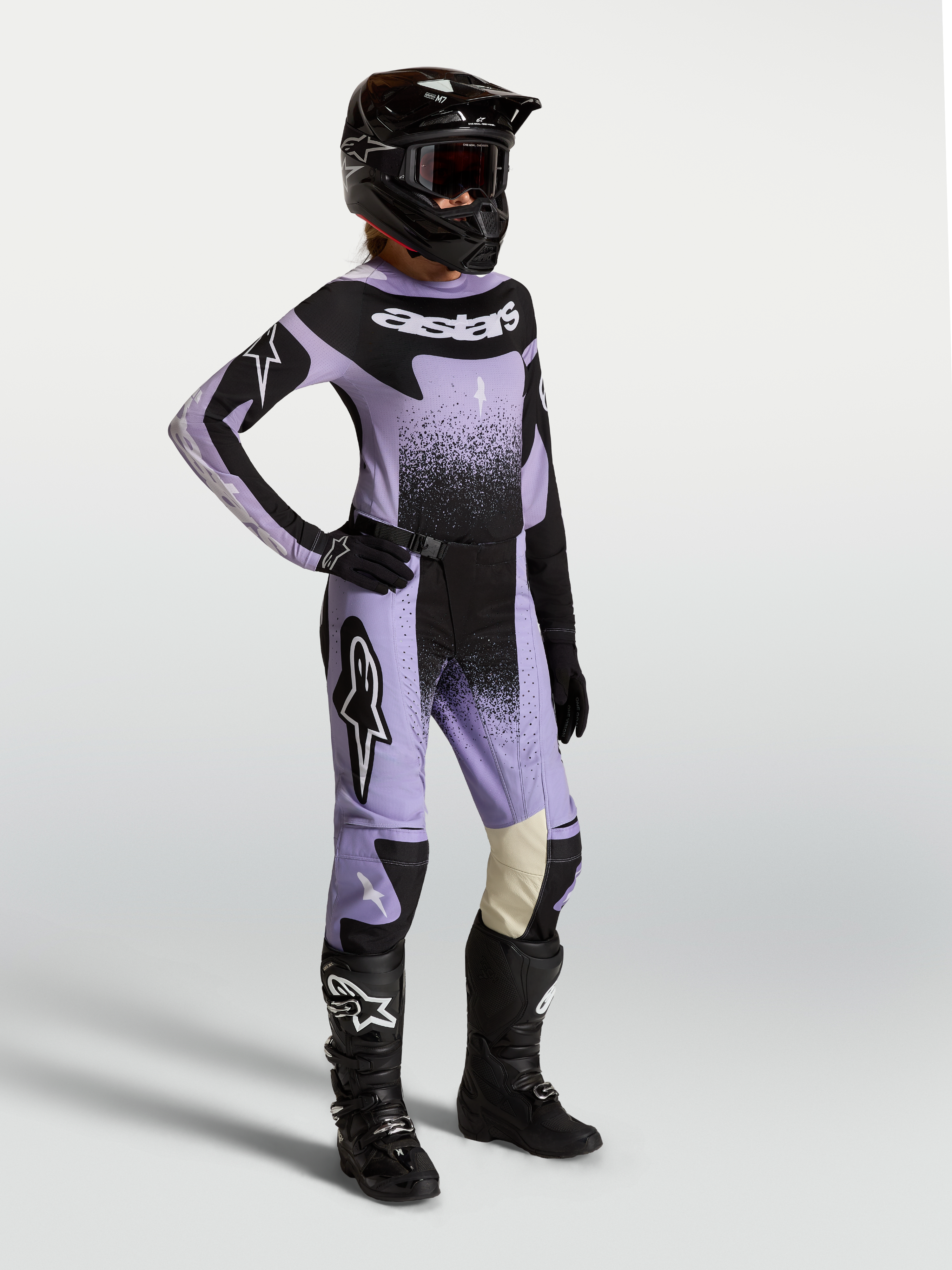 Alpinestars Stella Techstar Swan, completo motocross donna viola e nero con grafiche cigno, indossato con casco e stivali.