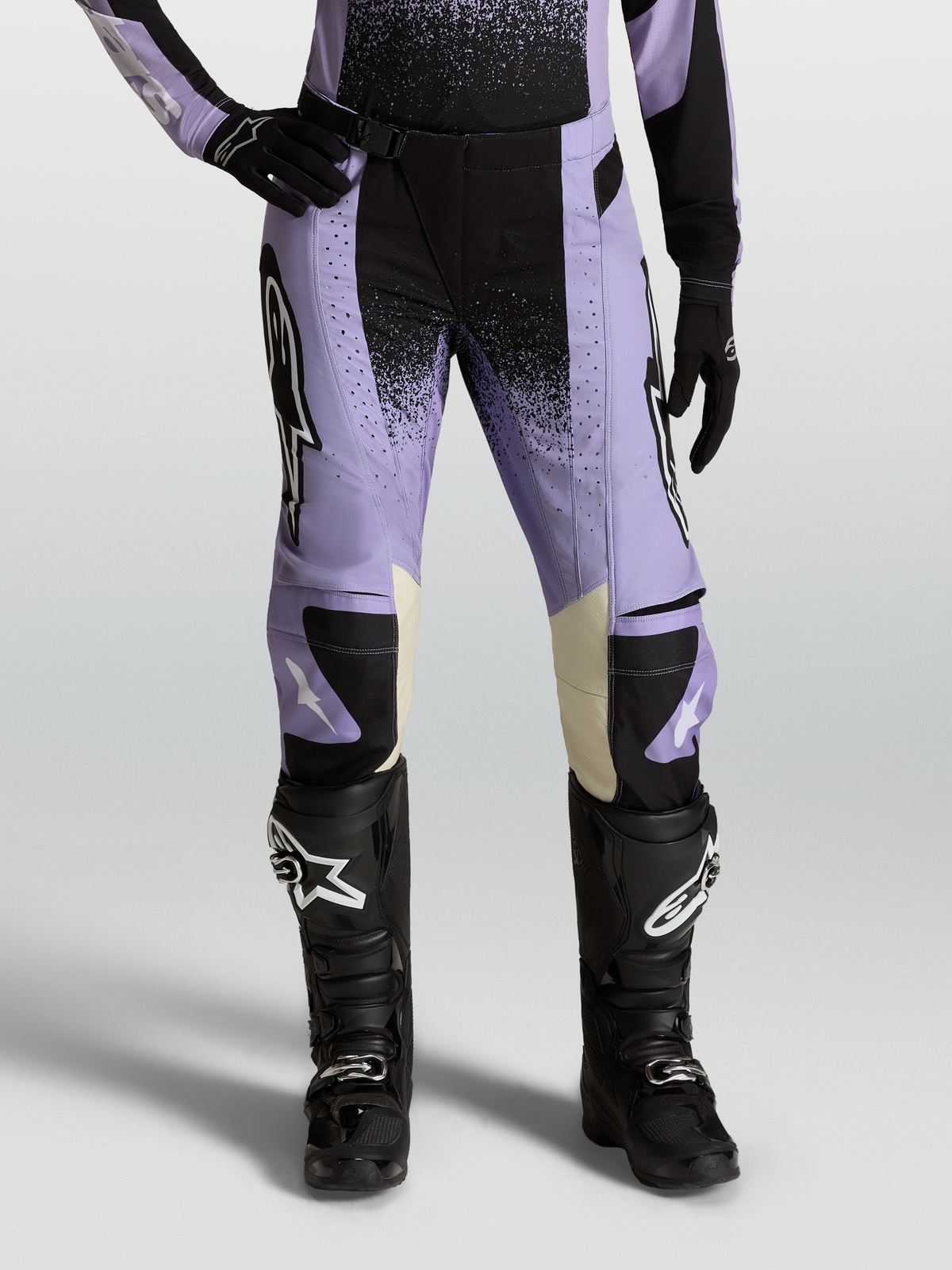Alpinestars Stella Techstar Swan, pantaloni motocross da donna, viola chiaro e nero, con interni ginocchia in pelle crema, abbinati a stivali neri.