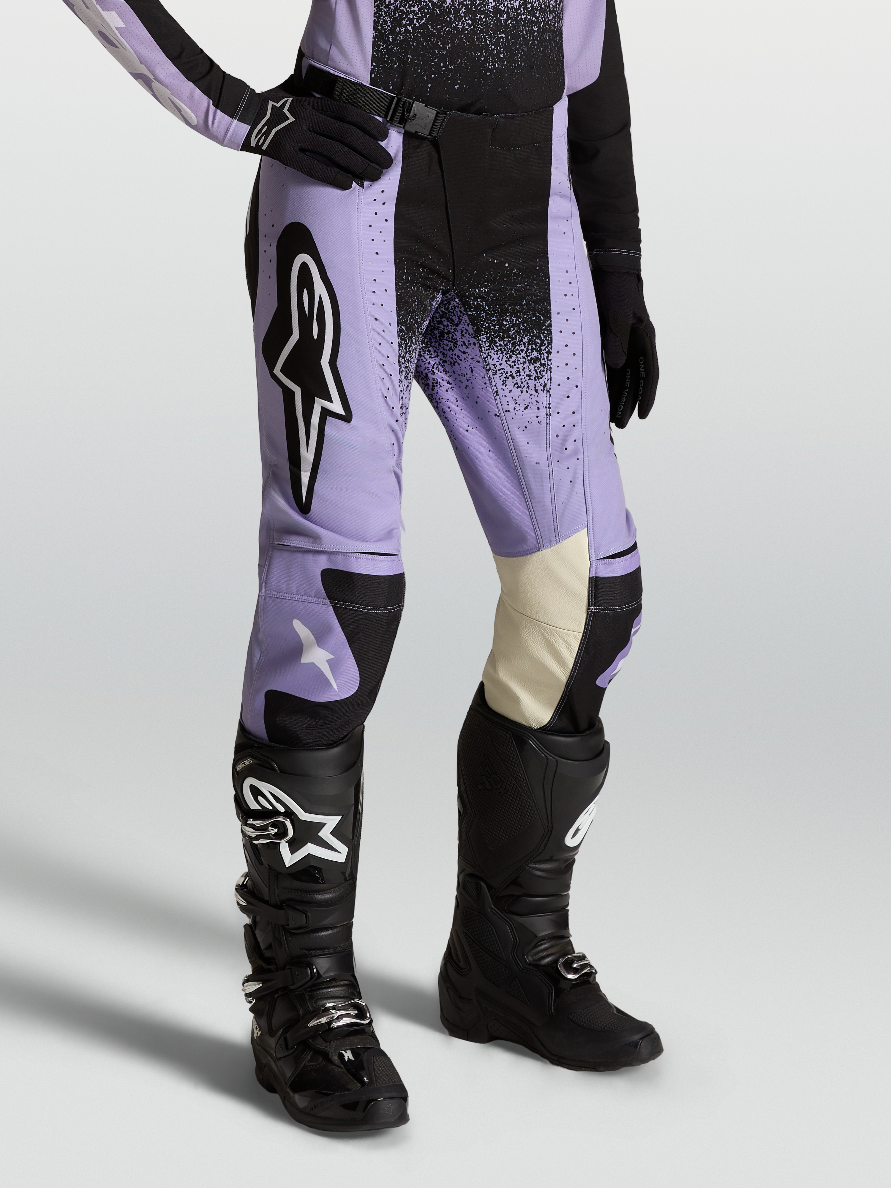 Alpinestars Pantaloni Stella Techstar Swan, pantaloni da motocross per donna, viola e nero, pannelli ginocchio in pelle bianca, indossati con stivali neri, abbigliamento fuoristrada premium