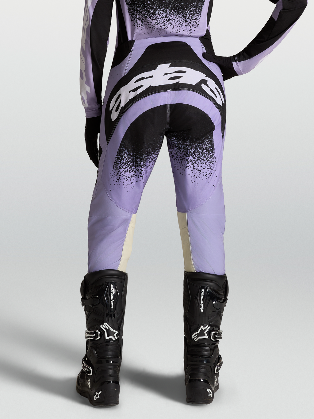 Alpinestars Pantaloni Stella Techstar Swan, pantaloni motocross da donna, viola e neri, indossati con stivali neri.