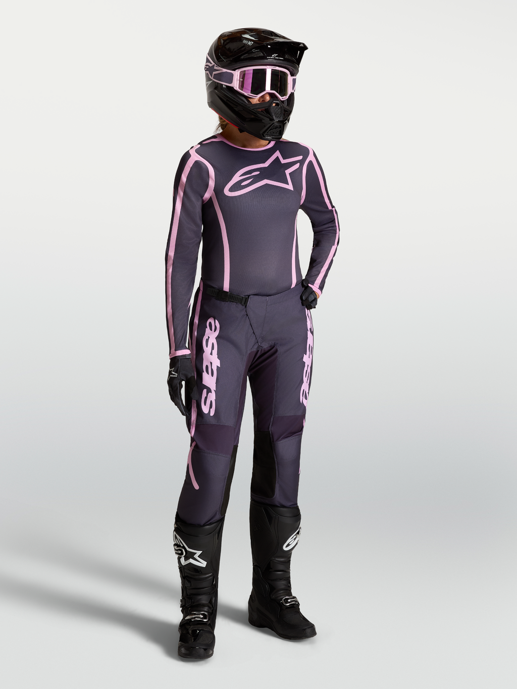 Maglia e completo Alpinestars Stella Fluid Apex V2, outfit da motocross da donna grigio e rosa con stivali da gara neri.