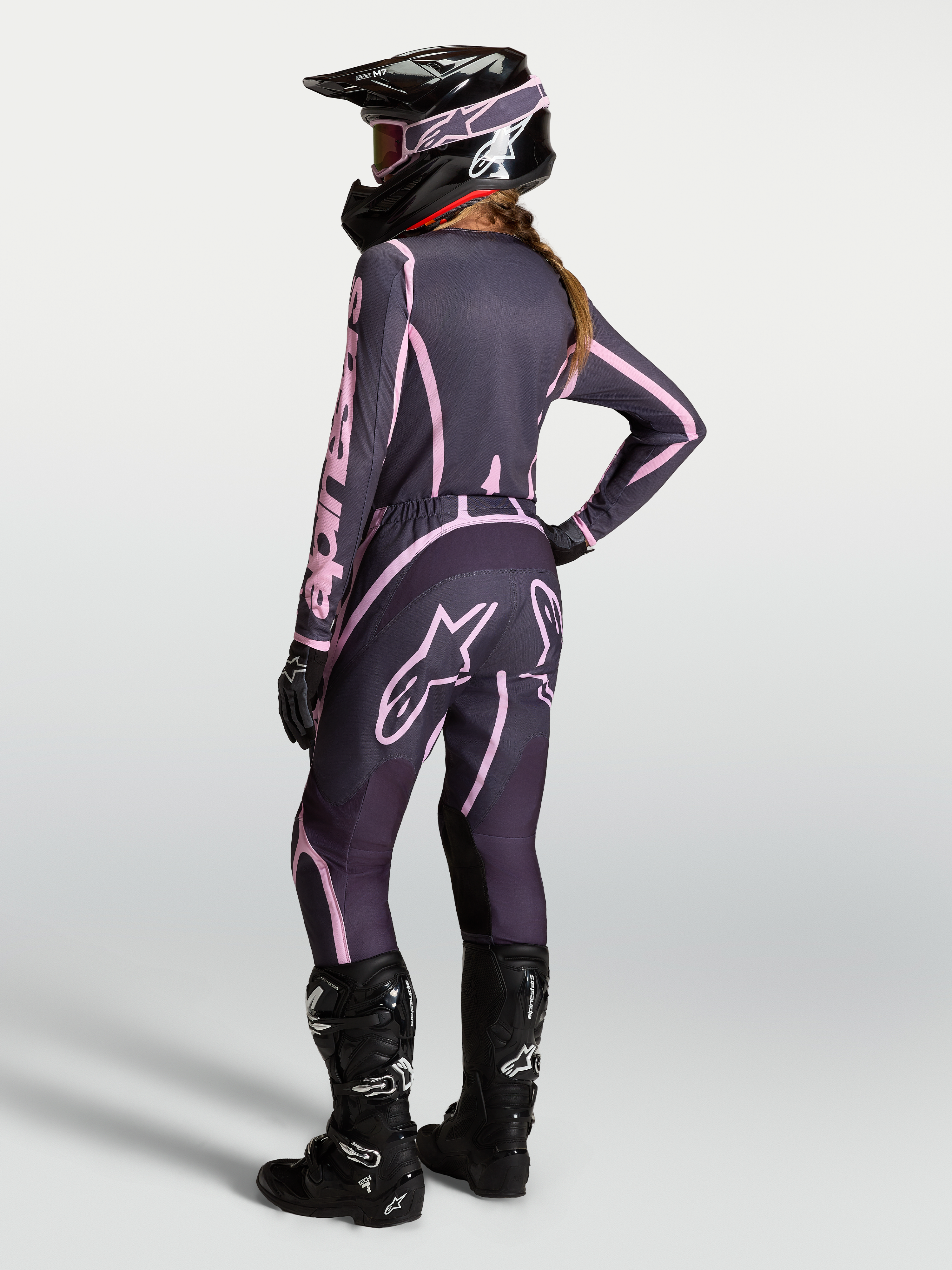 Alpinestars Maglia Stella Fluid Apex V2 AND Stella Fluid Apex V2 Gear Set, completo da motocross da donna, grigio e rosa, con stivali neri, modella vista di spalle