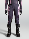 Alpinestars Pantaloni Stella Fluid Apex V2, pantaloni motocross da donna, grigio e rosa, chiusura a cricchetto e design precurvato, indossati con stivali neri per fuoristrada.