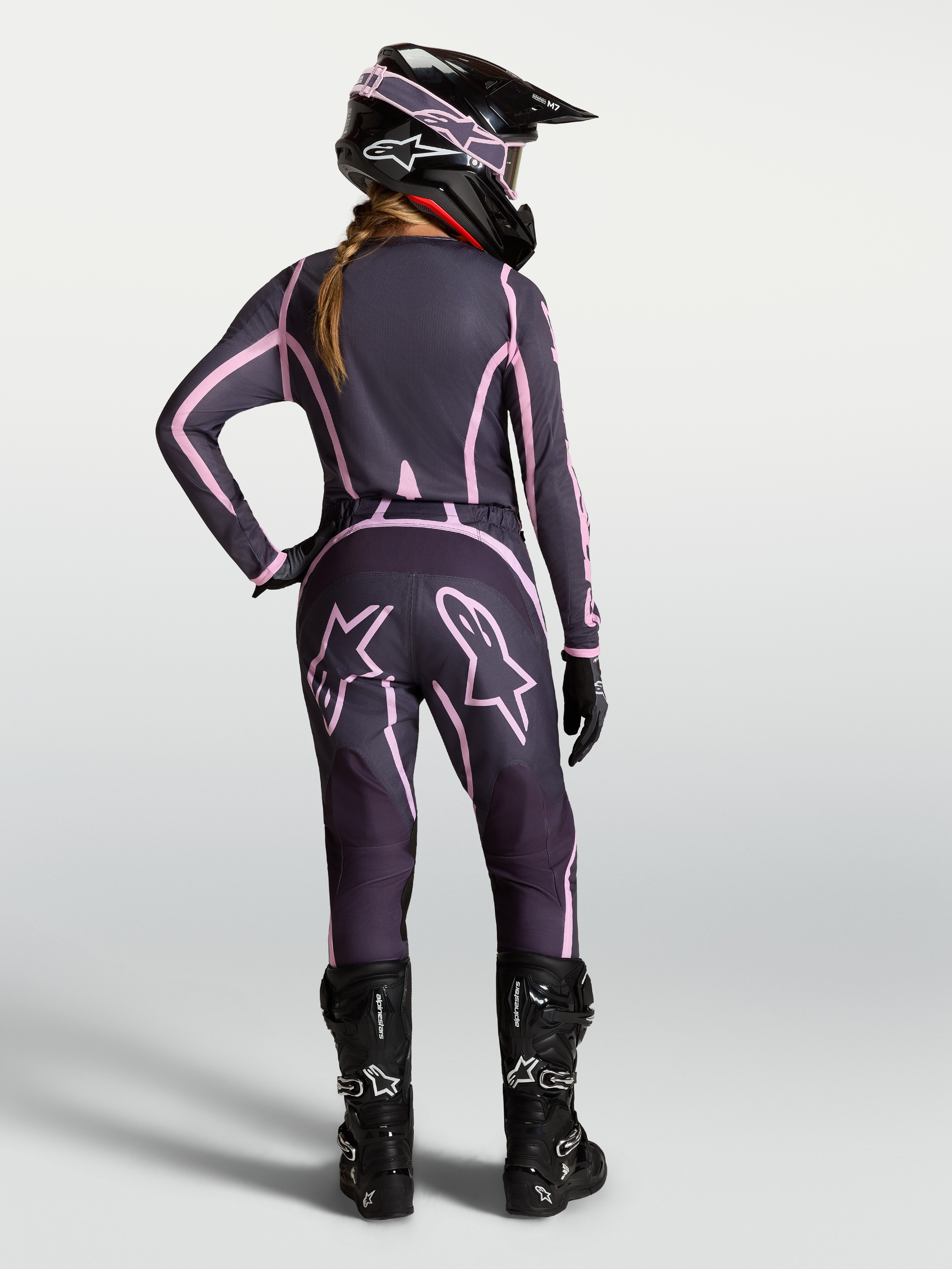 Alpinestars Pantaloni Stella Fluid Apex V2, pantaloni da motocross da donna, grigio e rosa, vista posteriore su modella con attrezzatura coordinata.
