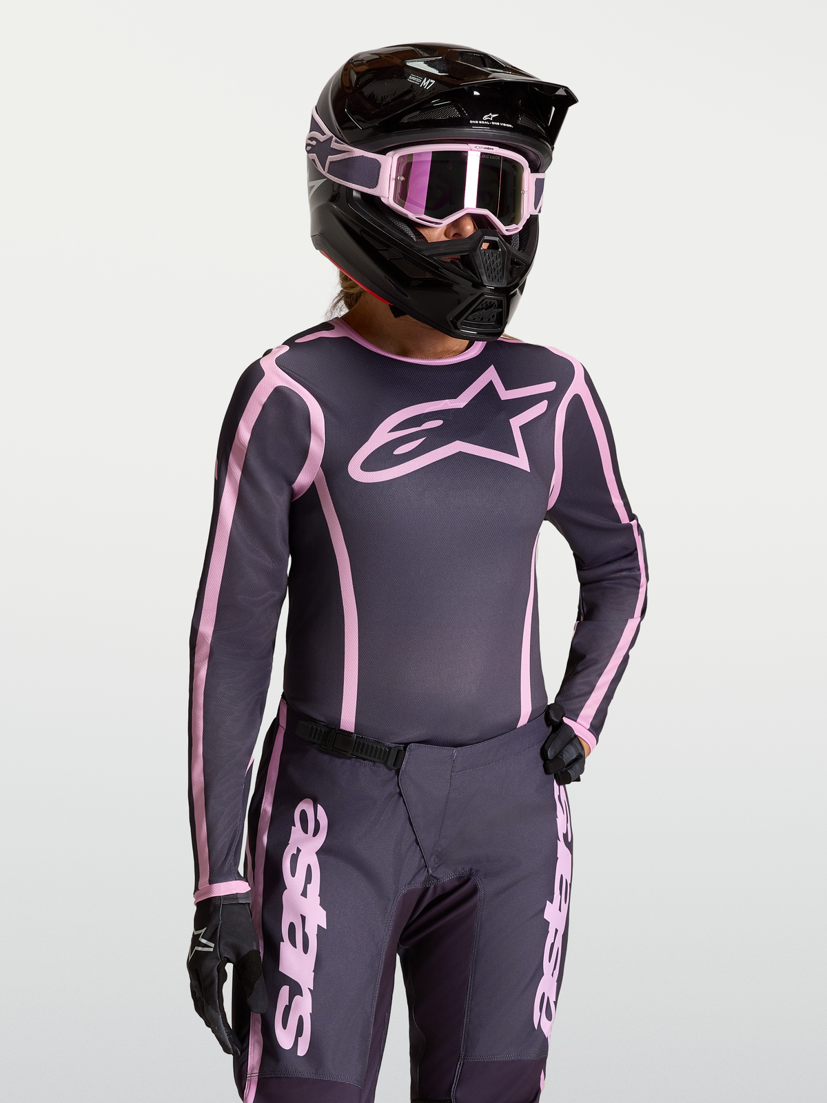 Alpinestars maglia Stella Fluid Apex V2, maglia da motocross da donna, grigio e rosa, tessuto traspirante con vestibilità ergonomica per prestazioni off-road, indossata con equipaggiamento coordinato.