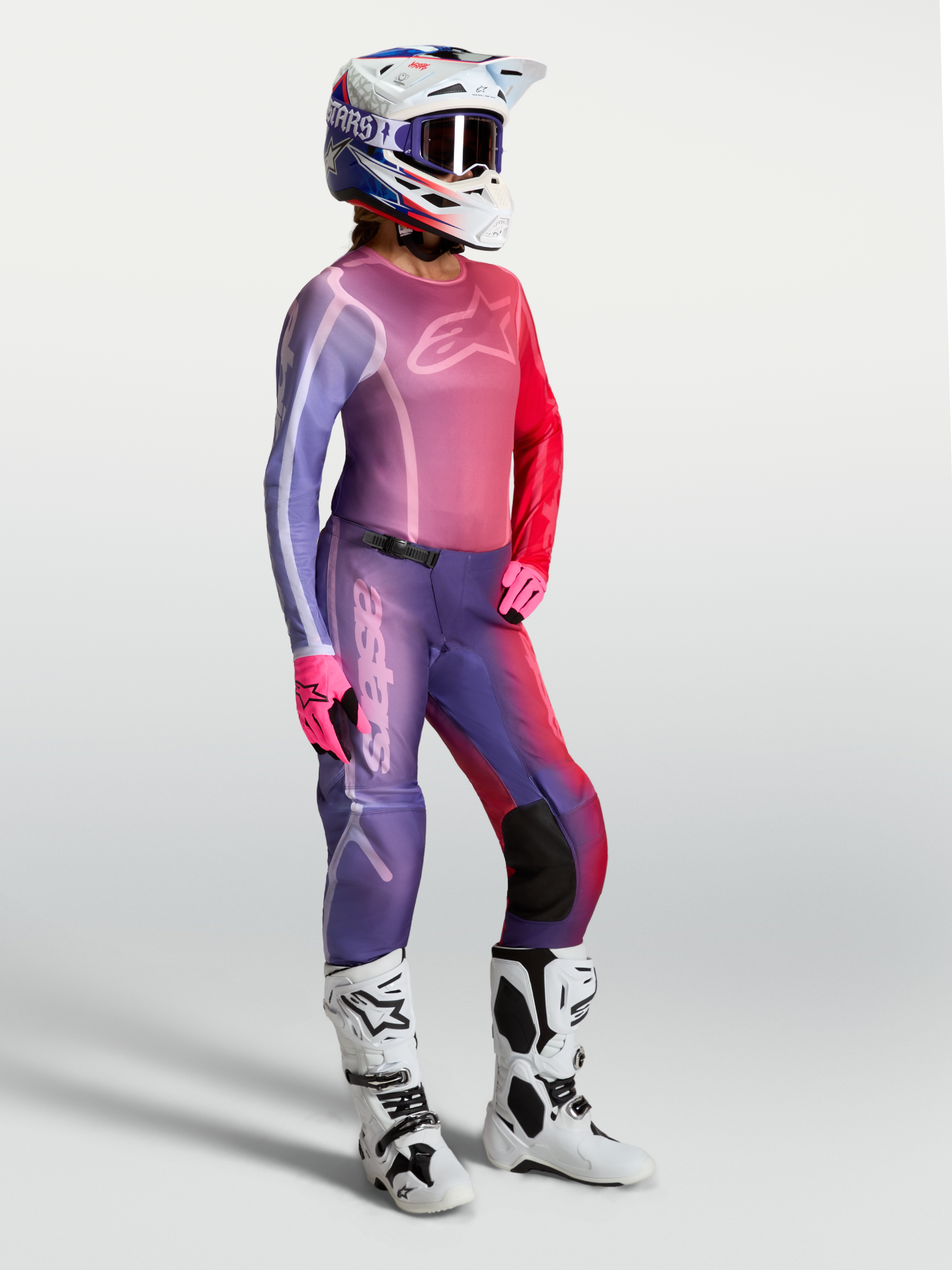 Alpinestars Maglia Stella Fluid Kepler, maglia da motocross per donna, viola e rossa, indossata con pantaloni coordinati e stivali bianchi, abbigliamento tecnico per fuoristrada e MX