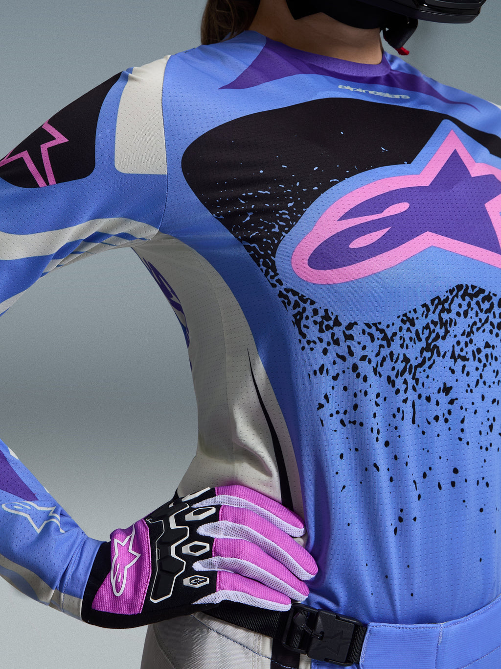 Alpinestars 2026 Stella Techstar Nomur Gear Set, completo motocross da donna, azzurro e nero con logo a stella rosa, indossato con guanti rosa e bianchi coordinati, vestibilità atletica da gara progettata per prestazioni d'eccellenza su tutti i terreni.