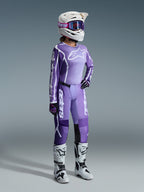 Set completo Alpinestars Stella Fluid Apex 2026, viola e lavanda, pilota di motocross donna che indossa maglia e pantaloni coordinati, casco bianco con occhiali viola, stivali bianchi e neri, guanti neri e viola, abbigliamento completo da performance per corse off-road femminili