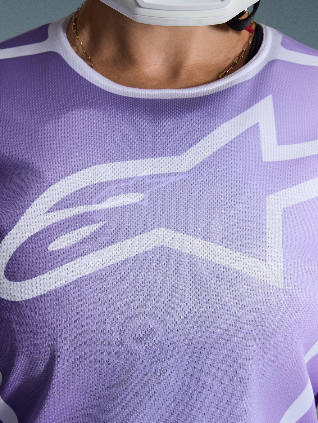 Alpinestars Stella Fluid Apex Jersey 2026, primo piano del petto, viola con grafiche bianche, caratterizzata da un grande logo Astars bianco su struttura in poli-tessuto mesh.