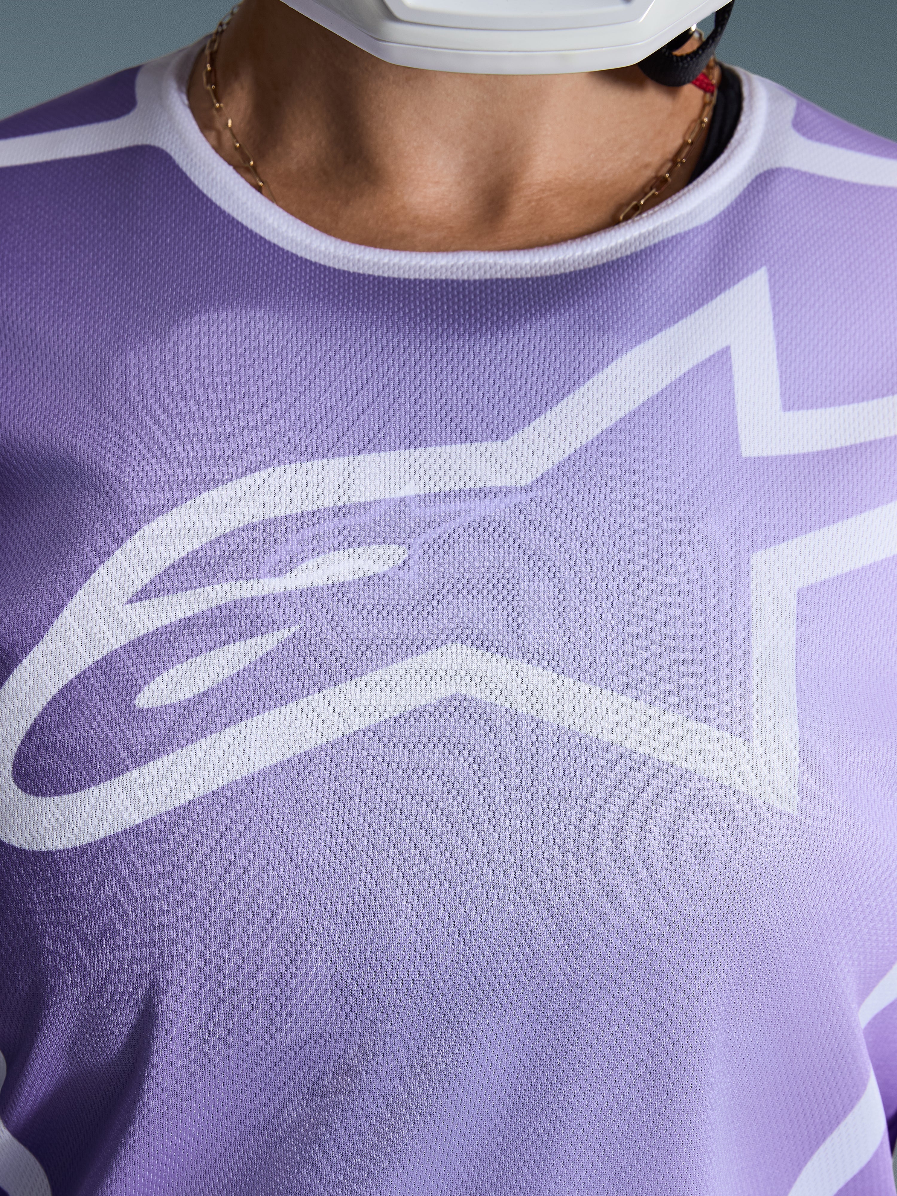 Alpinestars Stella Fluid Apex Jersey 2026, primo piano del petto, viola con grafiche bianche, caratterizzata da un grande logo Astars bianco su struttura in poli-tessuto mesh.