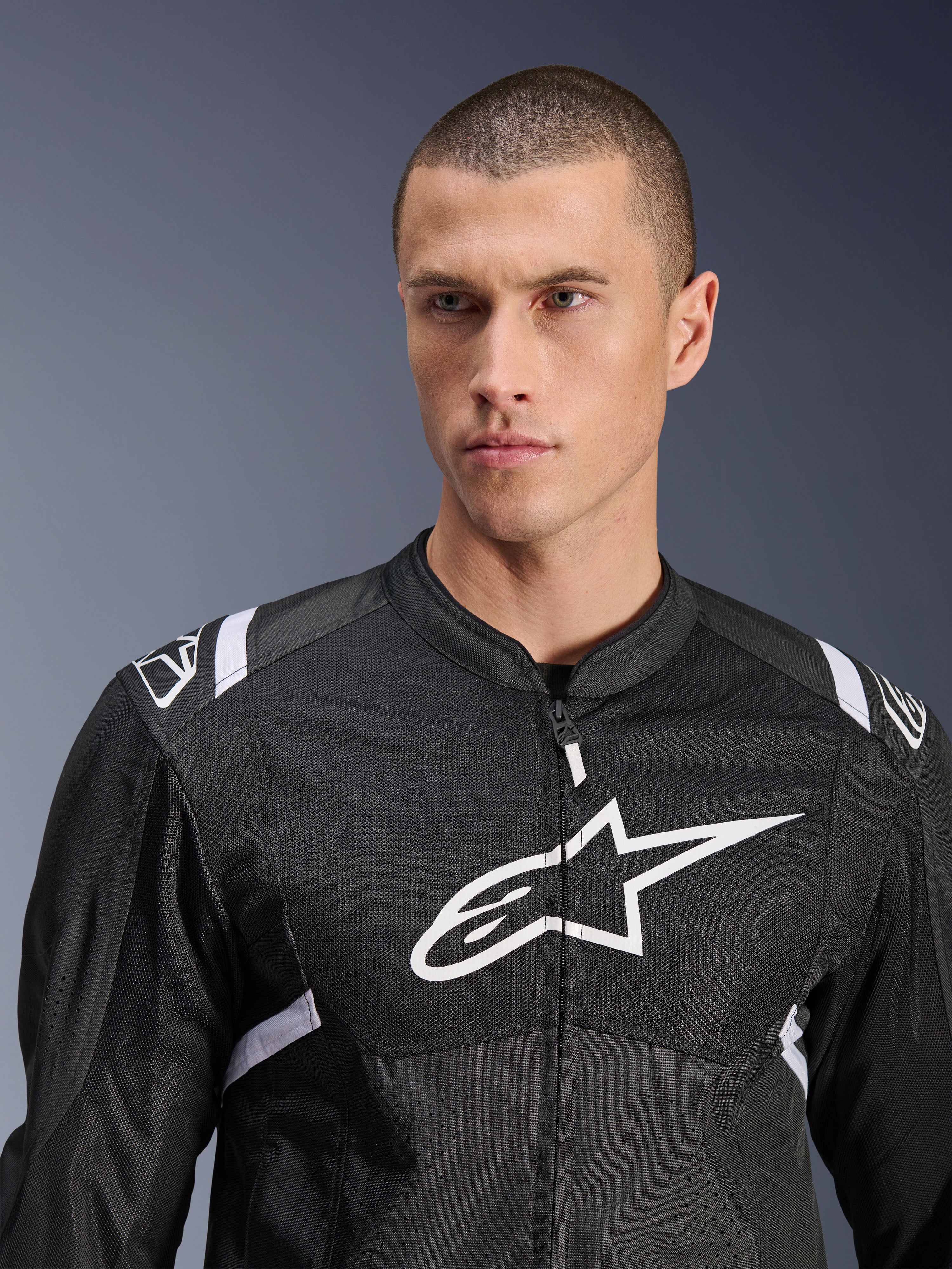 Giacca Alpinestars T-SPS Air V2, giacca da moto in tessuto, nero e bianco, con grande logo bianco sul petto e pannelli in mesh, vestibilità sportiva performante indossata da un modello