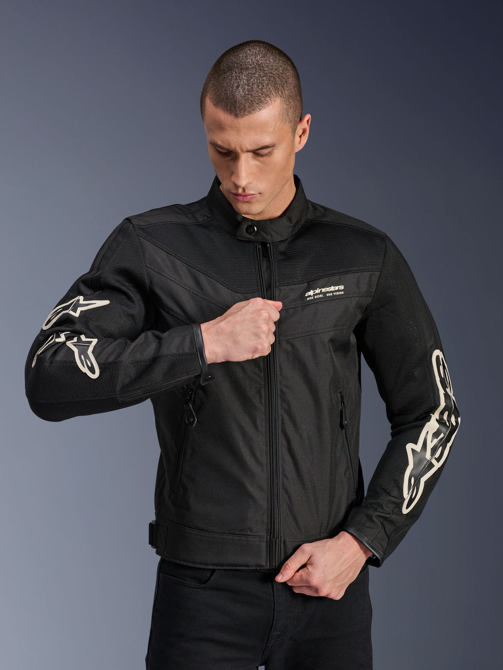 Alpinestars T-Dyno Air Jacket, nero, giacca da moto in tessuto con pannelli in rete 3D e loghi bianchi sulle maniche, indossata da un modello mentre chiude la zip frontale, stile urban street riding