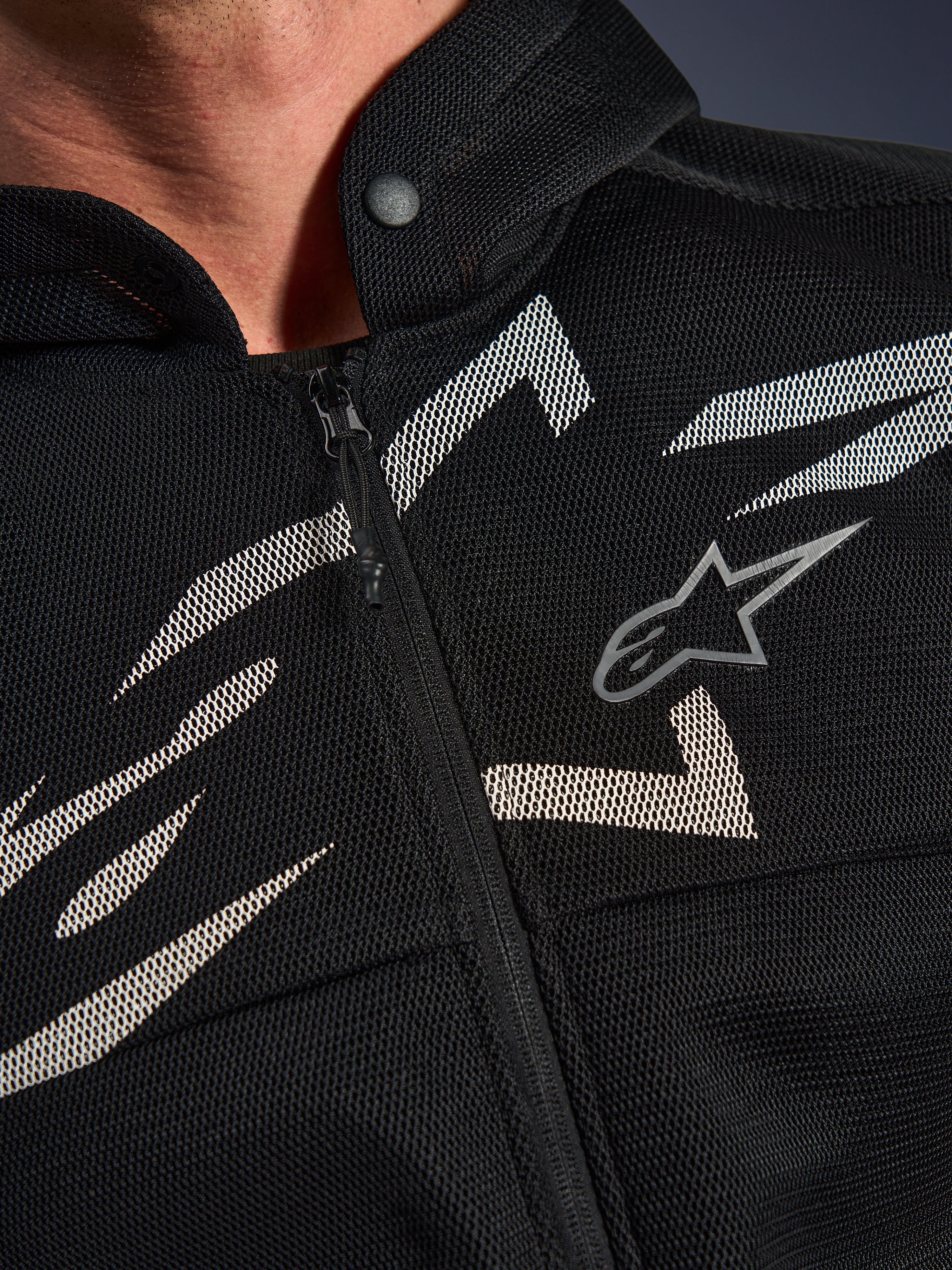 Alpinestars Chrome Superairflow Hoodie, felpa da moto, nera con grafiche bianche e grigie, primo piano del petto con costruzione in mesh tecnico 3D, cerniera anteriore e colletto con bottone a pressione, logo Alpinestars
