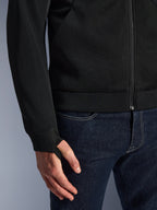 Alpinestars Chrome Superairflow Hoodie, nero, dettaglio del tessuto in mesh tecnico 3D ad alta resistenza, con polsino in maglia a coste elasticizzata e asola elastica per il pollice, indossata con jeans blu
