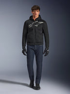 Motociclista che indossa la felpa Alpinestars Chrome Superairflow in nero e grigio, abbinata a jeans blu scuro, guanti da moto neri e scarpe nere. La felpa presenta un grande logo stilizzato sul petto e una trama in mesh 3D per prestazioni elevate con alte temperature.