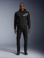 Alpinestars Chrome V2 Sport Hoodie, felpa da moto nera e bianca, grande logo Alpinestars bianco sul petto, zip frontale e cappuccio, indossata da un modello con pantaloni e stivali neri, abbigliamento protettivo da guida urbana