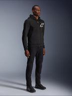 Alpinestars Chrome V2 Sport Hoodie, felpa da moto nera con logo a stella bianco, indossata da un modello con pantaloni neri coordinati e scarpe da moto, abbigliamento da guida urban lifestyle