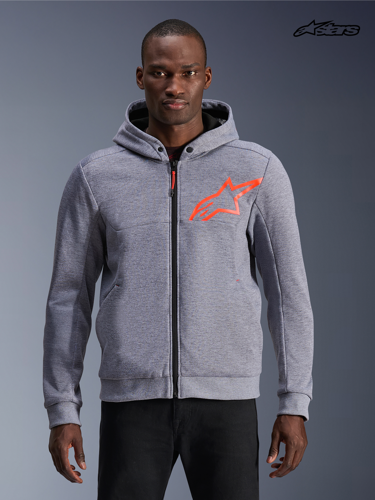 Alpinestars Felpa Con Cappuccio Chrome V2 Sport, felpa da moto urbana da uomo in grigio mélange con accenti rosso fluo, vista frontale su un modello che mostra la costruzione in pile tecnico e il design protettivo con cerniera