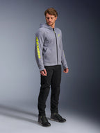 Alpinestars Chrome V2 Sport Hoodie, grigio melange e giallo fluo, indossata da un modello con pantaloni neri e scarpe da moto nere, con logo giallo vivace sulla manica e sul petto, abbigliamento da moto casual urbano