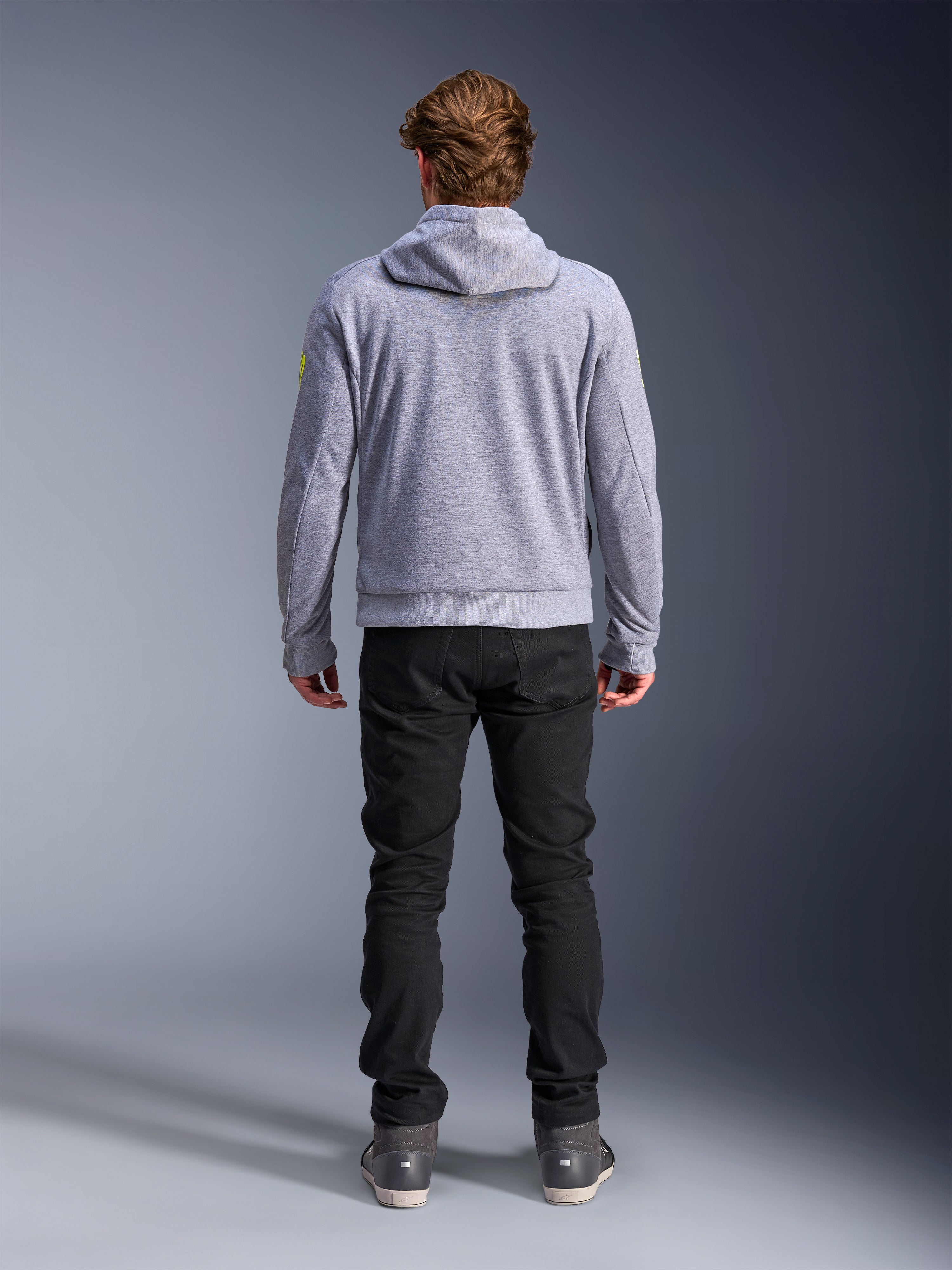Alpinestars Chrome V2 Sport Hoodie, grigio melange giallo fluo, vista posteriore di abbigliamento da moto urbano, felpa con cappuccio in pile tecnico indossata con pantaloni neri, con accenti giallo fluo sulle maniche