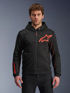 Alpinestars Chrome Air Sport Hoodie, felpa nera con cappuccio e zip, logo a stella rosso fluo e dettagli sulle maniche, pannelli laterali in mesh rosso per la ventilazione, abbigliamento urban riding casual indossato da un modello
