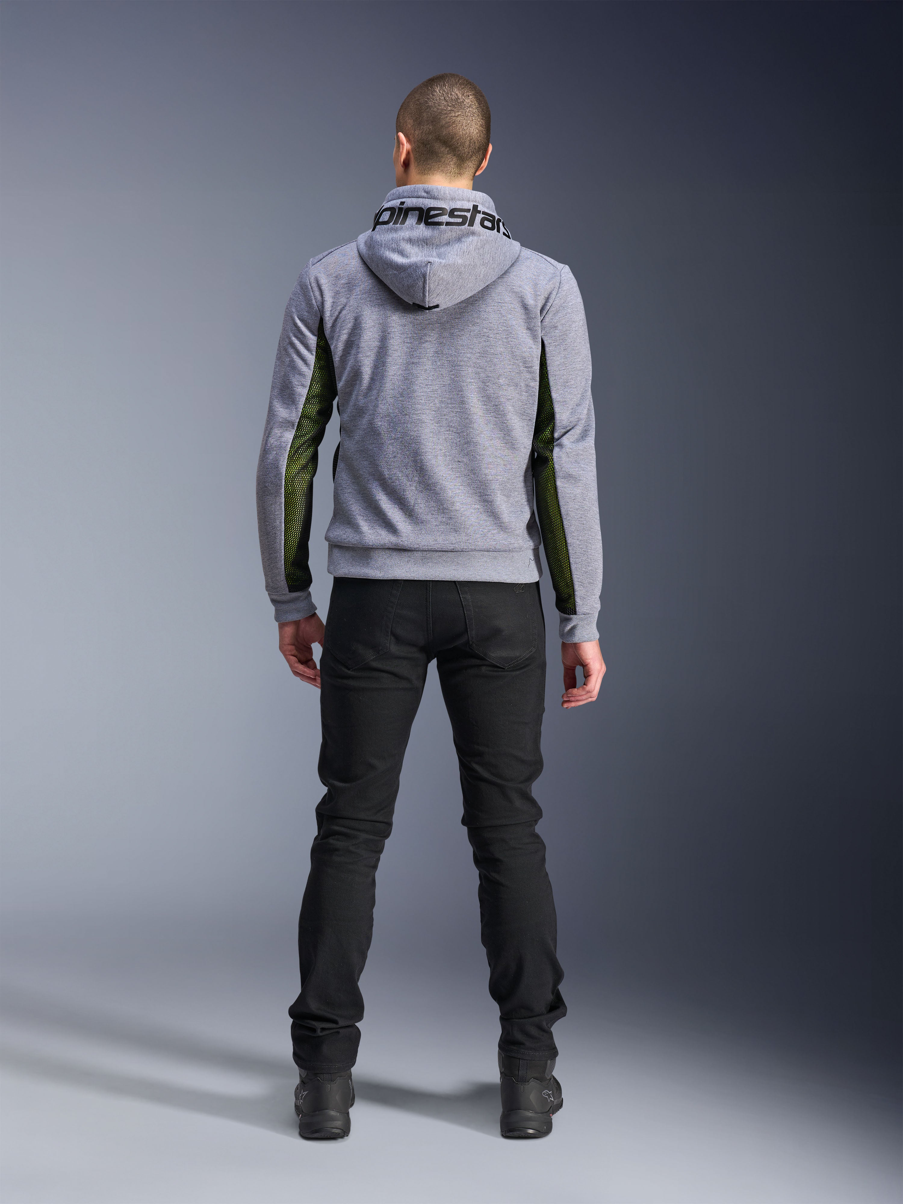 Alpinestars Chrome Air Sport Hoodie, Grigio Heather Nero, vista posteriore della felpa da moto con pannelli in mesh verde ad alto flusso sui lati e sulle maniche, costruzione in pile tecnico con marchio Alpinestars sul cappuccio, indossata con pantaloni neri