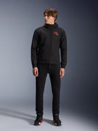 Alpinestars MM93 Radium Tech Hoodie, felpa da moto urbana nera, con logo 93 rosso e logo a stella bianco sul petto, indossata da un modello con pantaloni neri e scarpe da guida coordinate, guscio tecnico antivento per la guida urbana