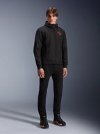Alpinestars MM93 Radium Tech Hoodie, giacca da moto urban, nero con accenti rosso brillante, indossata da un modello con pantaloni neri e scarpe da moto, con logo '93' rosso sul petto e marchio Marc Marquez sulla manica, streetwear tecnico casual per la guida urbana