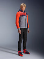 Alpinestars MM93 Chrome V2 Sport Hoodie, felpa da moto urbana, corpo grigio melange con petto blu navy e maniche rosso fluo acceso, con logo 93 sul petto, indossata da un modello con pantaloni neri slim-fit e scarpe da moto alte coordinate rosse e blu, vestibilità atletica moderna per la guida urbana