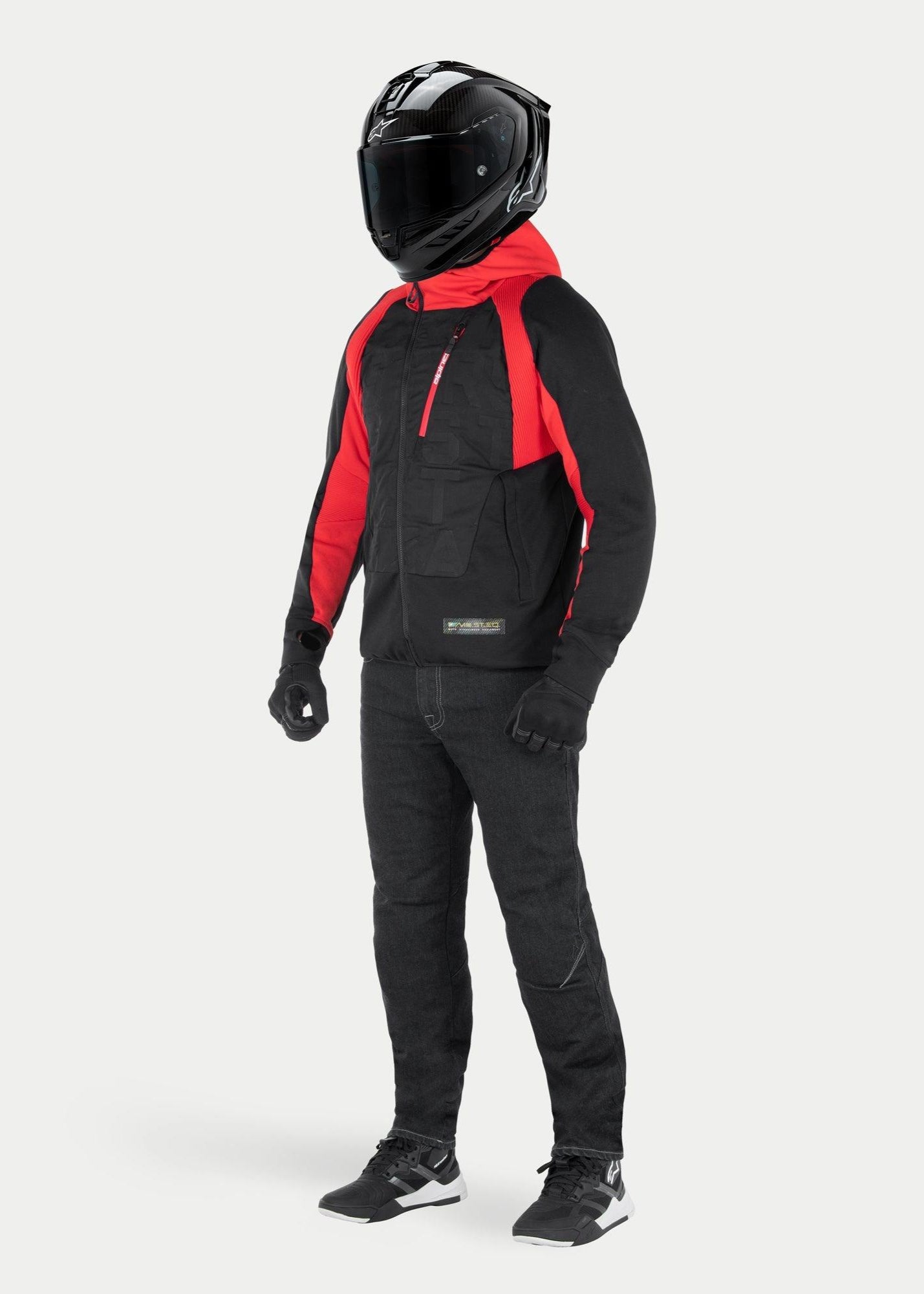 Giacca con cappuccio Alpinestars MO.ST.EQ Hybrid in Black Flame Red, felpa da moto urbana con cappuccio e dettagli sulle spalle rossi, indossata con casco integrale nero e pantaloni da guida, design contemporaneo ispirato allo streetwear