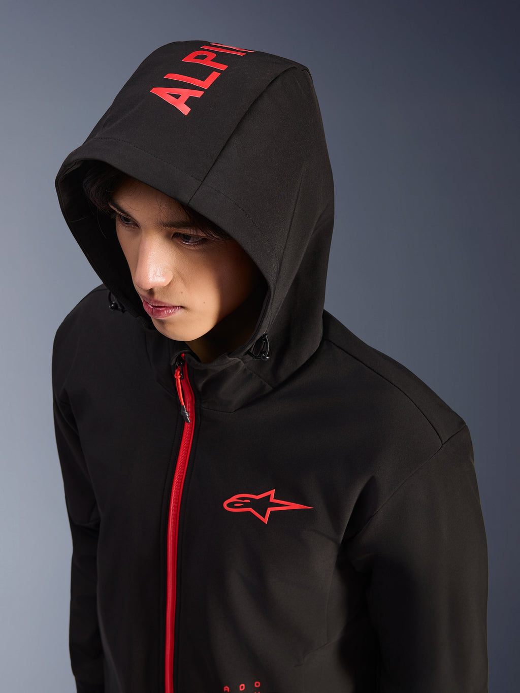 Alpinestars Radium Tech Hoodie, nero e rosso acceso, felpa tecnica da moto stile urban, logo Alpinestars rosso sul petto e scritta rossa sul cappuccio, cerniera rosso acceso, streetwear moderno ispirato al motorsport