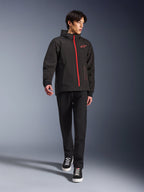 Alpinestars Radium Tech Hoodie in Black Bright Red, giacca da moto urbana indossata da un modello, caratterizzata da una cerniera frontale rossa e logo sul petto, abbinata a pantaloni neri e sneaker per un look da commuting moderno.