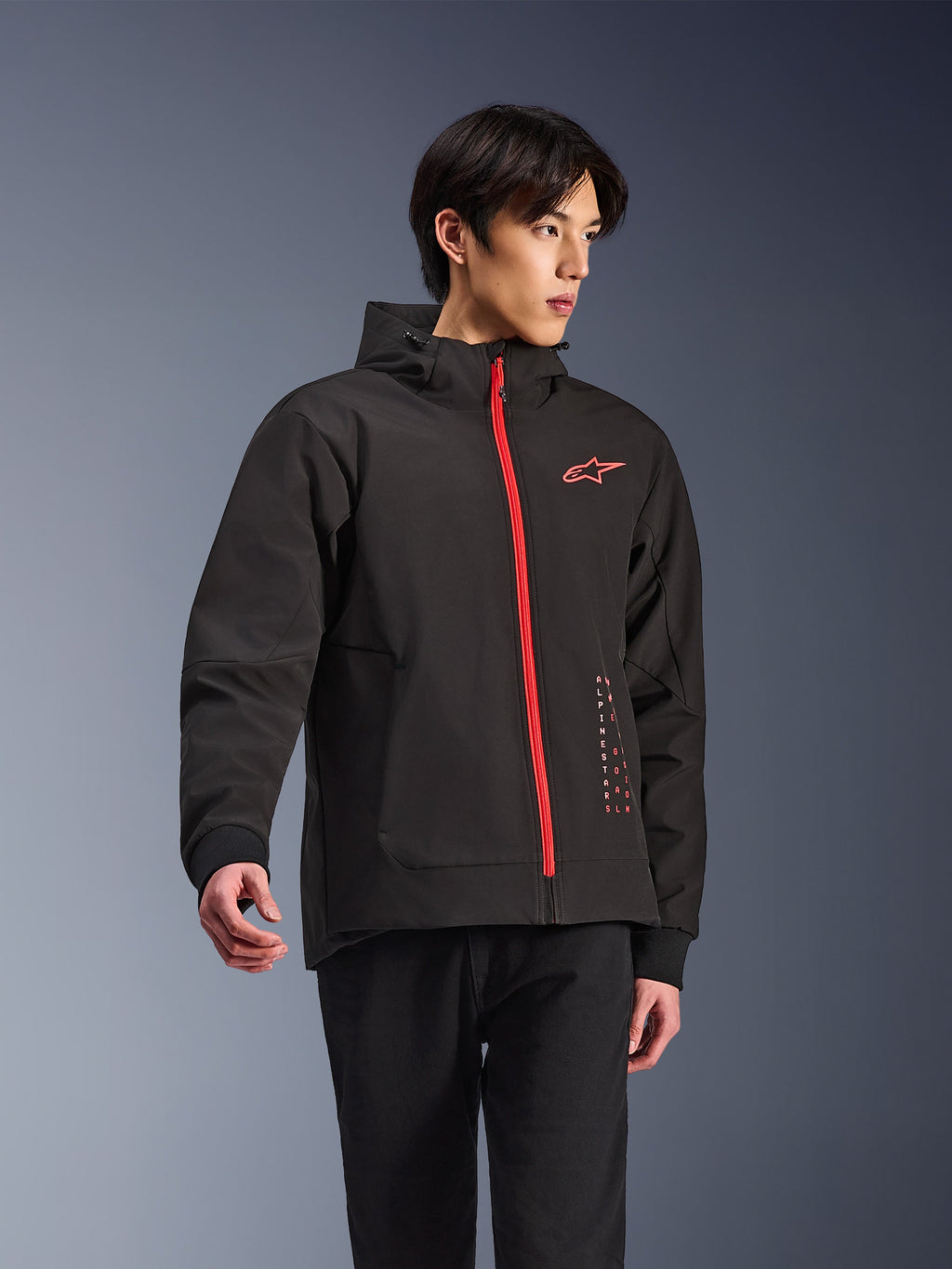Alpinestars Radium Tech Hoodie, giacca da moto urbana, nero con zip rosso vivace, logo Alpinestars rosso sul petto e scritte rosse laterali, guscio tecnico antivento con cappuccio e polsini a coste, stile street moderno per motociclisti