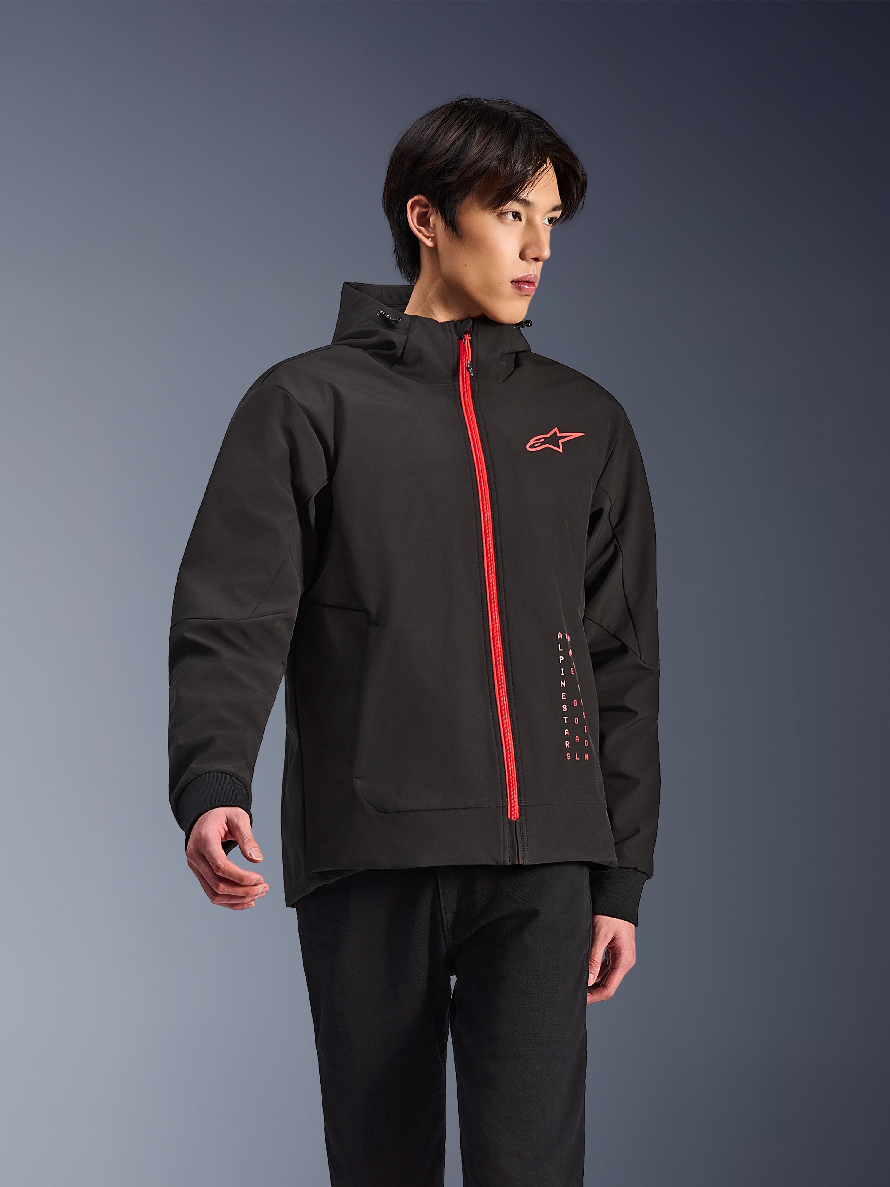 Alpinestars Radium Tech Hoodie, giacca da moto urbana, nero con zip rosso vivace, logo Alpinestars rosso sul petto e scritte rosse laterali, guscio tecnico antivento con cappuccio e polsini a coste, stile street moderno per motociclisti