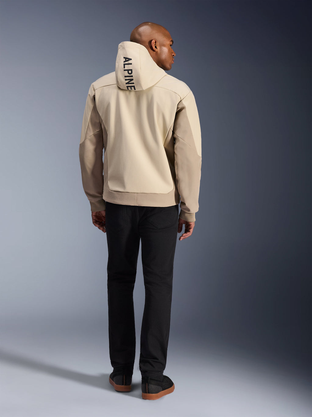 Alpinestars Radium Tech Hoodie, Mastic Aluminum, vista posteriore con scritta verticale 'ALPINE' sul cappuccio, giacca da moto urbana in guscio tecnico 3L antivento con pannelli beige, indossata con pantaloni neri