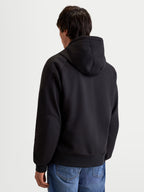 Alpinestars Felpa Con Cappuccio Ageless, felpa da moto urbana da uomo, colore nero, vista posteriore su un modello che mostra il cappuccio fisso e la struttura in tessuto