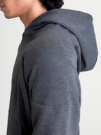 Alpinestars Felpa Con Cappuccio Ageless, felpa da moto urbana da uomo, grigio asfalto melange, vista ravvicinata del profilo laterale con dettagli della costruzione in tessuto a maglia e rinforzo sulla spalla indossata da un modello