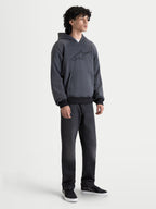 Alpinestars Felpa Con Cappuccio Ageless, felpa da moto urbana da uomo, colore grigio asfalto melange, vista frontale su un modello che indossa abbigliamento da guida casual