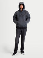 Alpinestars Felpa Con Cappuccio Ageless, felpa da moto urbana da uomo in grigio asfalto melange, vista frontale su un modello con cappuccio indossato, tasca a marsupio anteriore e protezioni integrate su spalle e gomiti