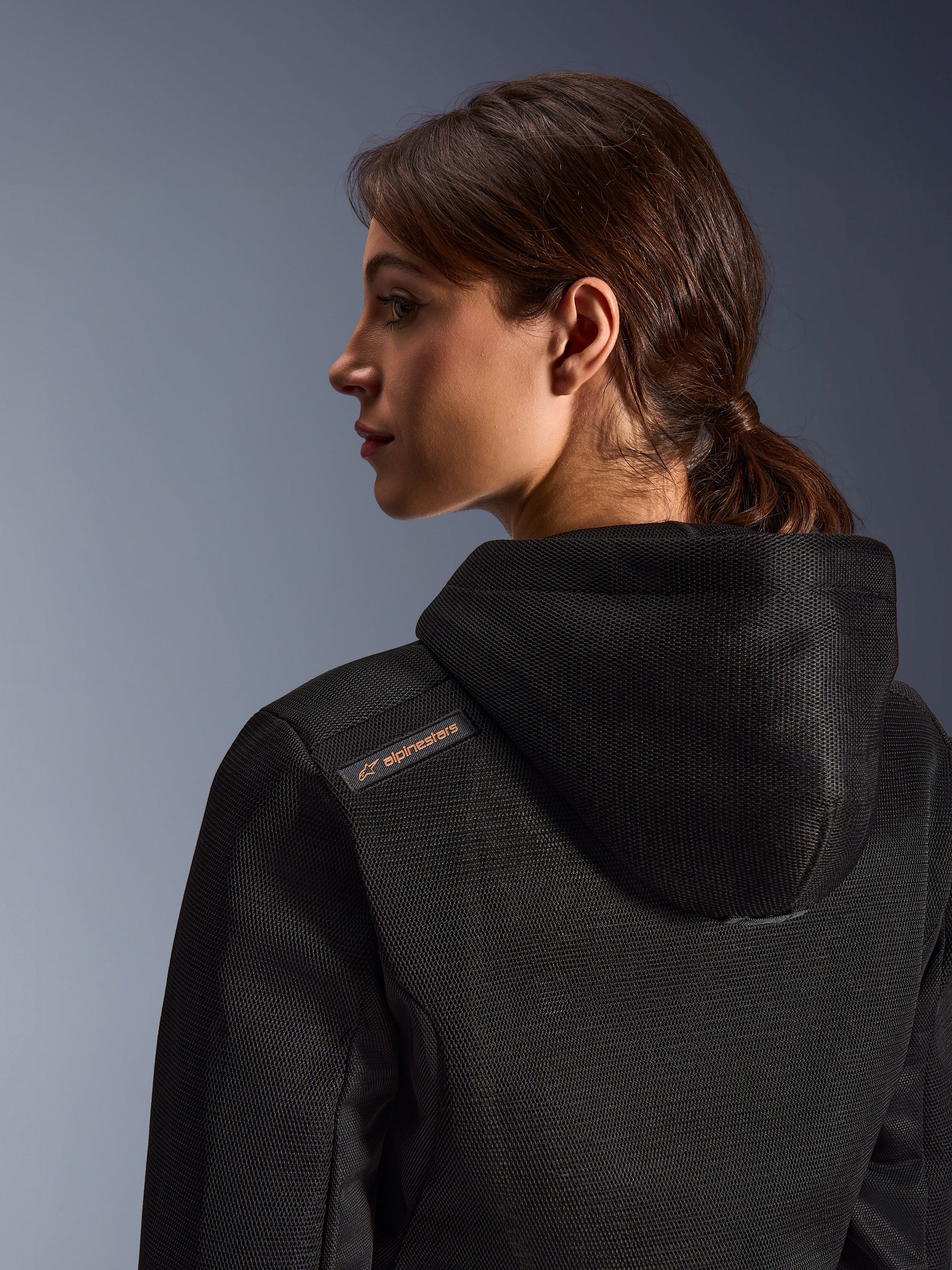 Alpinestars Stella Chrome Superairflow Hoodie, felpa da moto da donna, nera con dettaglio del logo color rame, primo piano della costruzione in mesh 3D sulla schiena e sulla spalla, abbigliamento protettivo tecnico per guida sportiva urbana