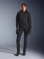 Modella che indossa la Alpinestars Stella Chrome Superairflow Hoodie in nero, abbinata a pantaloni tecnici e guanti da guida neri, caratterizzata da una costruzione in mesh 3D e logo sul petto color rame, abbigliamento da moto urban sport per donna