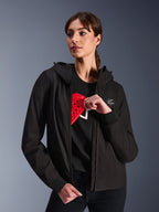 Alpinestars Stella Radium Tech Hoodie da donna, felpa da moto urbana nera, modella che mostra la protezione rossa Nucleon Flex Plus all'interno, guscio in tessuto tecnico a 3 strati leggero e antivento con polsini a coste e patch con logo sul petto, abbigliamento protettivo da moto