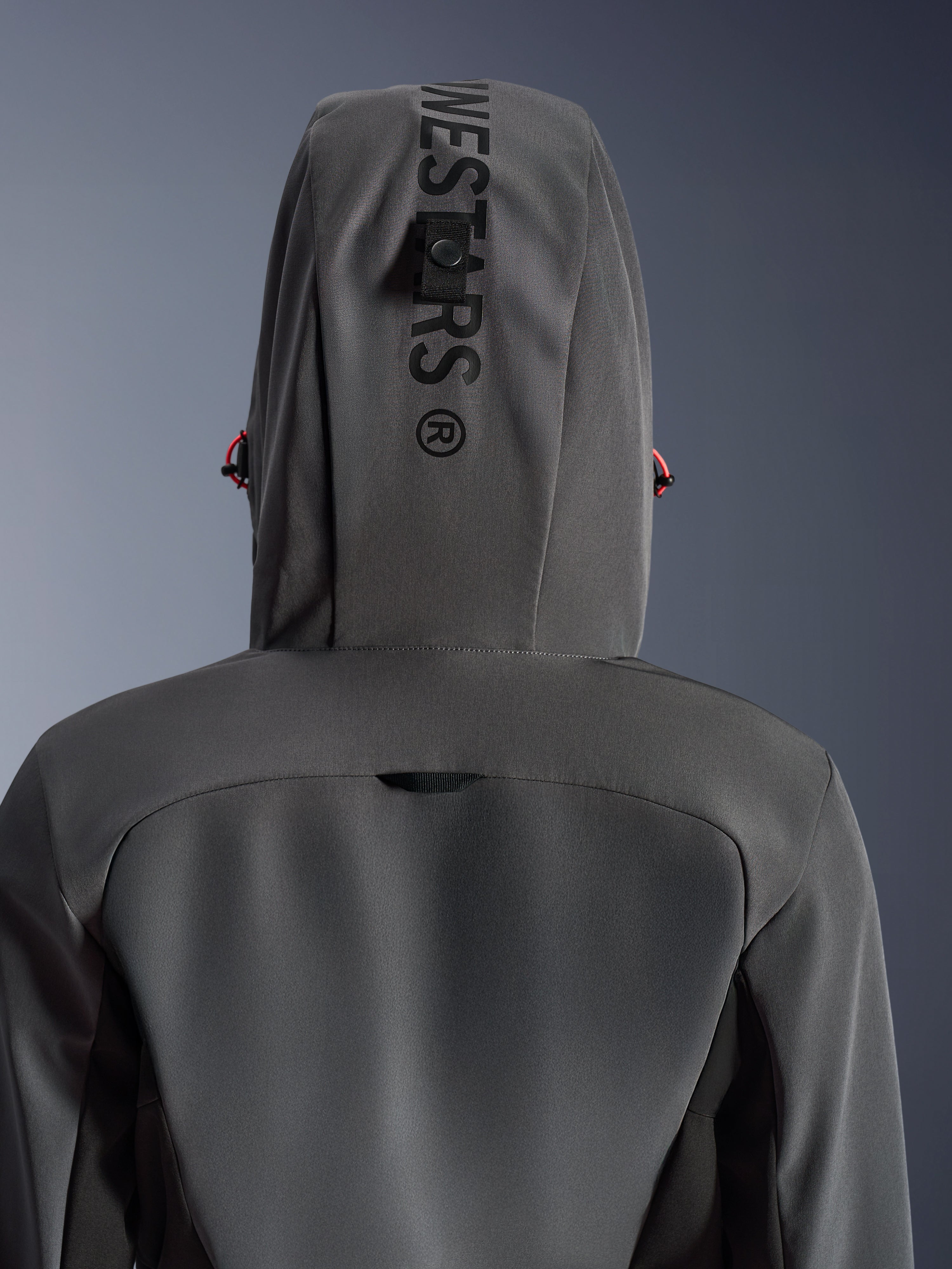 Alpinestars Stella Radium Tech Hoodie da donna, Deep Gray Black, vista posteriore ravvicinata del cappuccio con branding verticale e asola di fissaggio, dettagli dei cordini rossi, resistente costruzione in tessuto tecnico a 3 strati antivento per la guida motociclistica urbana.
