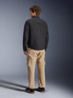 Alpinestars Bryon WR Overshirt, nero, vista posteriore su modello, abbinata a pantaloni cargo color sabbia e sneakers nere, giacca da moto urbana con texture in tela cerata e design posteriore minimalista