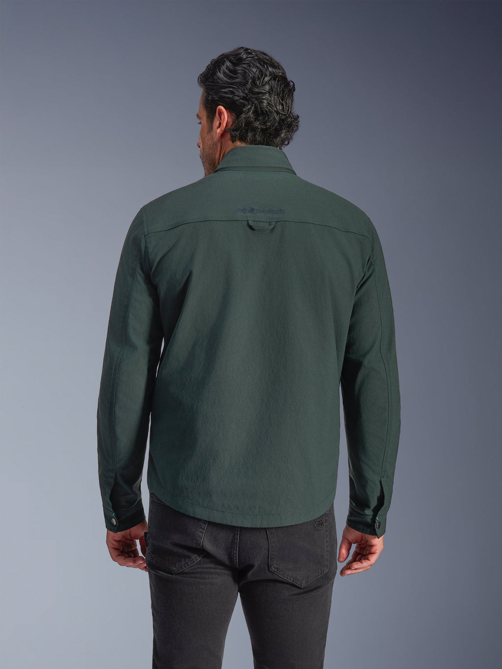 Alpinestars Bryon Water Resistant Overshirt, verde smeraldo scuro, vista posteriore su modello, logo ricamato sulla parte superiore della schiena, tela cerata resistente, giacca da moto urbana abbinata a pantaloni scuri