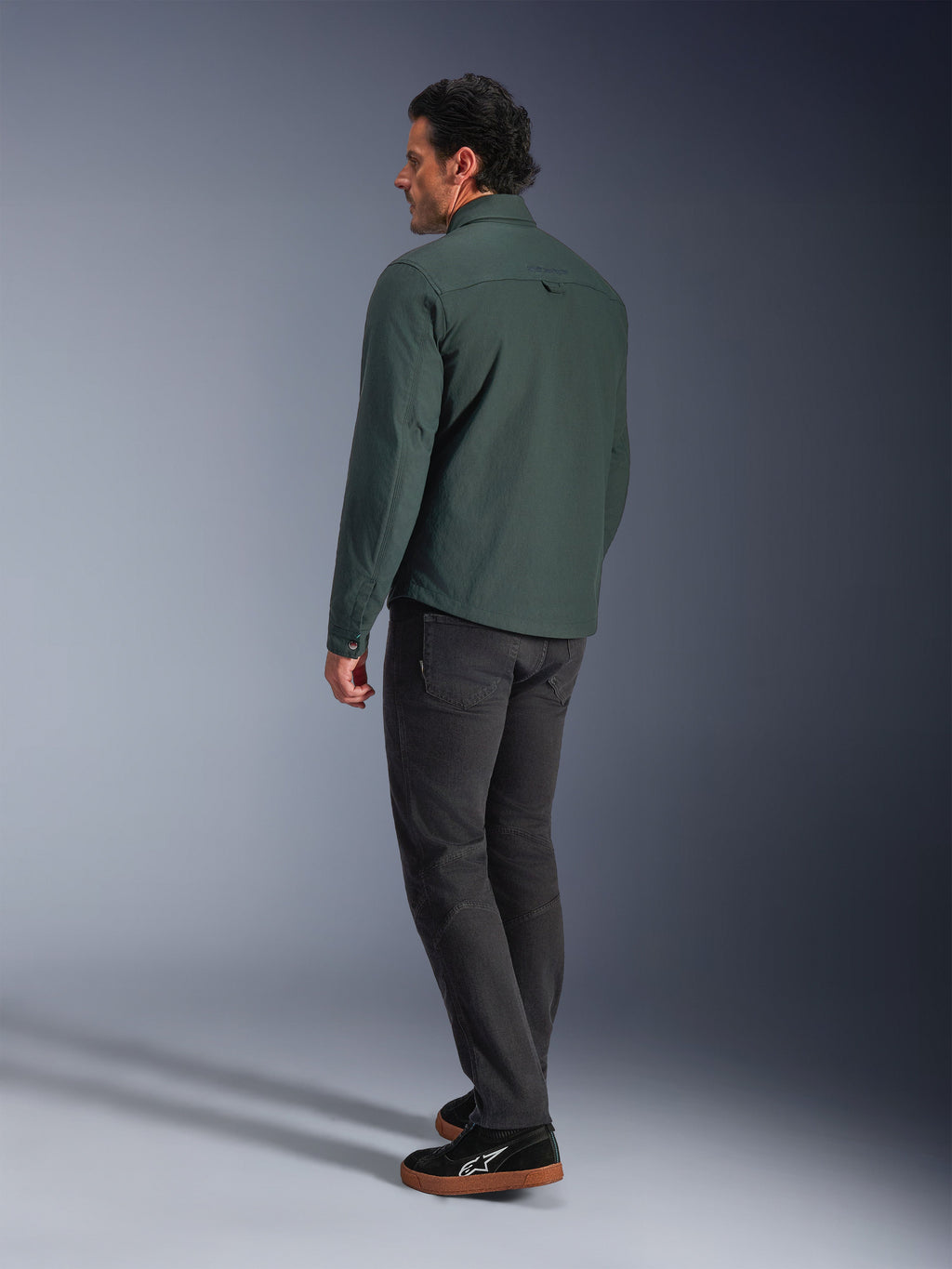 Alpinestars Bryon Water Resistant Overshirt, verde Dark Emerald, vista posteriore di una giacca da moto urbana, indossata con pantaloni scuri e sneakers nere, design moderno ispirato all'abbigliamento da lavoro