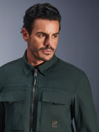 Alpinestars Bryon Water Resistant Overshirt in Dark Emerald, primo piano di un uomo che indossa la giacca da moto urban, con texture in tela cerata, zip frontale con discreti accenti teal, tasche cargo sul petto e patch con logo del marchio.