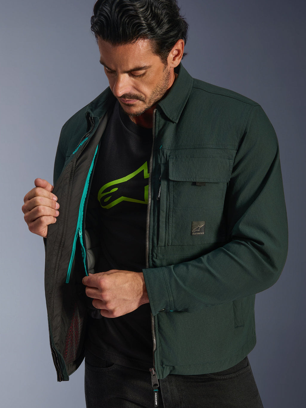 Alpinestars Bryon Water Resistant Overshirt, Dark Emerald, vista lifestyle del modello che mostra il gilet termico interno e il dettaglio della zip color ottanio, giacca da moto urbana in tela cerata e tasche cargo