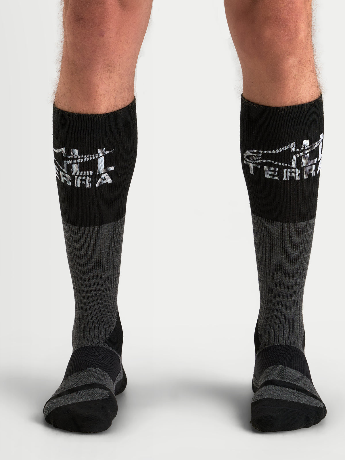Alpinestars At 8 Merino Calzini, calzini da moto adventure da uomo in grigio e nero, capo termico in misto lana merino indossato da un modello che mostra il polpaccio a coste e le zone di ammortizzazione rinforzate